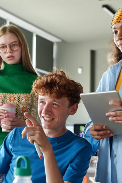Three students collaborating on project using computer in team during IT class in school or college