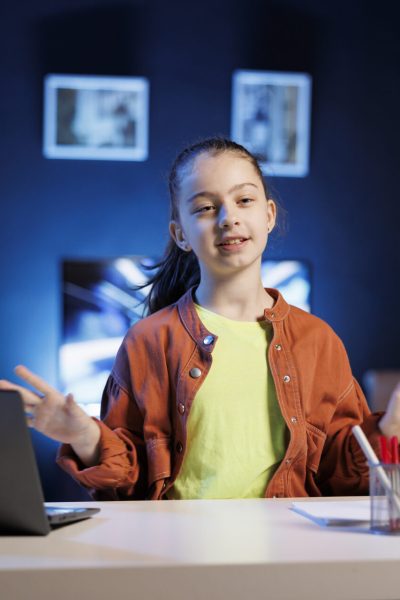 Young content creator using professional recording camera and microphone to do livestream. Kid online streamer using video production gear to do live broadcast for her audience