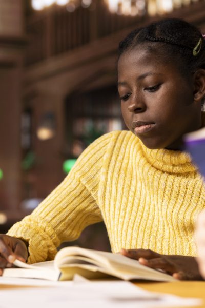Young teenagers reading literary texts at the library as part of their curriculum, preparing for literature class lesson and enhancing their academic focus. Girls read the mandatory books titles.
